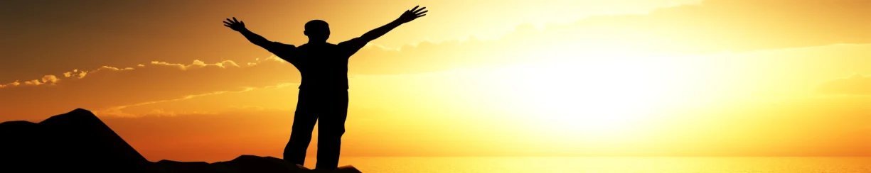 Silhouette of a person with arms raised towards a vibrant sunset